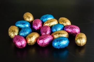 Chocolate Easter eggs in colorful foil on dark background