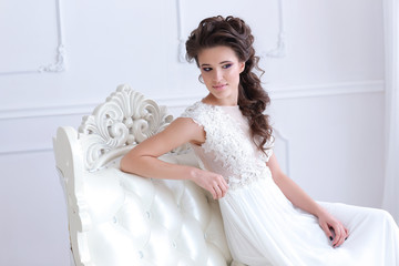 Young gorgeous bride is sitting in antique armchair