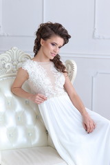 Young gorgeous bride is sitting in antique armchair