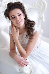 Young gorgeous bride is sitting in antique armchair