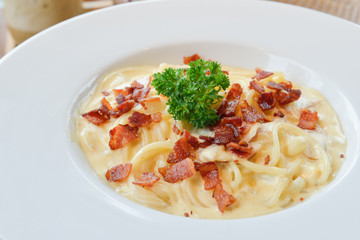Spaghetti carbonara with ham, cheese and parsley