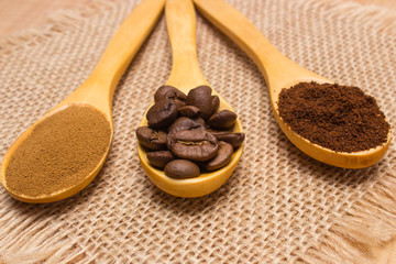 Grains, ground and instant coffee with wooden spoon on jute canvas