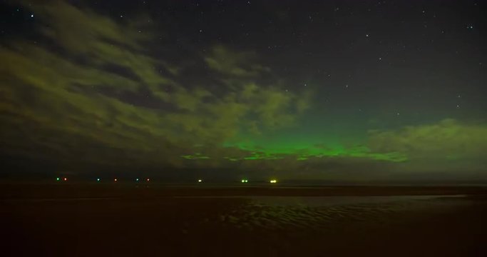 Aurora Borealis (Northern Lights) behind clouds on a beach of the Baltic Sea