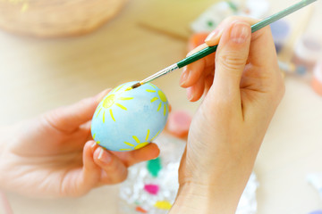 Female hands painting Easter eggs at table indoors