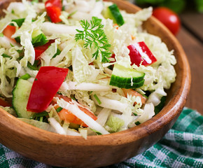 Vegetarian vegetable salad (cabbage, tomato, paprika, cucumber, onion) in a wooden bowl