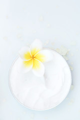 Obraz na płótnie Canvas Top view of organic cream with frangipani flower