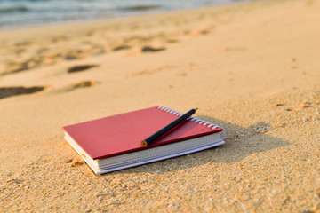 Red book and pencil on beach sunset sunrise