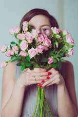 Cute bridesmaid hiding behind a bouquet of rose flowers.