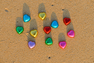 Red and colorful chocolate hearts candies on beach