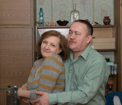 Aged man is embracing girlfriend closing his eyes.