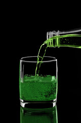 The lemonade is poured into a glass on black background