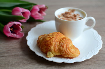 cup of coffee and yummy croissant with flowers