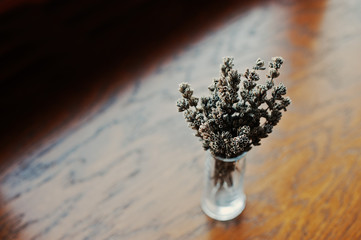 Dried lavender branches at vase at brown wooden background