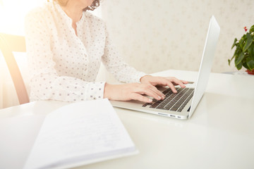 Portrait of a mature beautiful businesswomen enjoying, work on portable laptop computer, charming adult female using net-book while sitting in office or home interior.