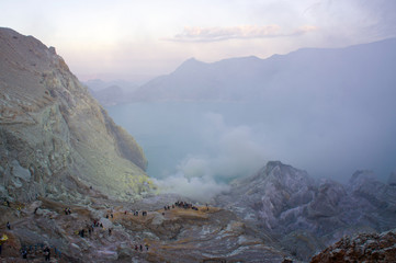 Ijen volcano in East Java contains the world's largest acidic volcanic crater lake, called Kawah Ijen, spewing out sulphur smoke in the morning. Sun is hidden in mist.