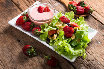 Salad with strawberry and cornflakes on wooden background