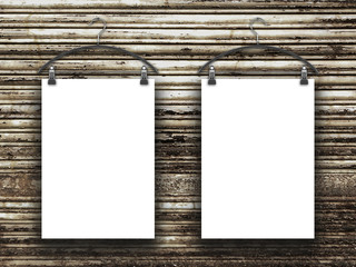 Close-up of two hanged blank frames with clothes hangers against rusty brown metal shutter background