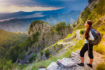 Obraz premium Woman traveler with backpack standing on big cliff in the mountains.