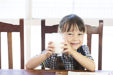 a school uniform little girl is drinking milk