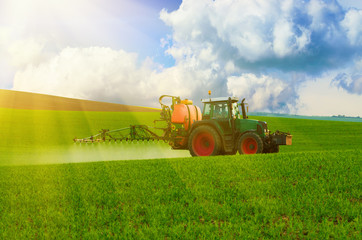 Obraz premium Farm machinery spraying insecticide to the green field, agricultural natural seasonal spring background