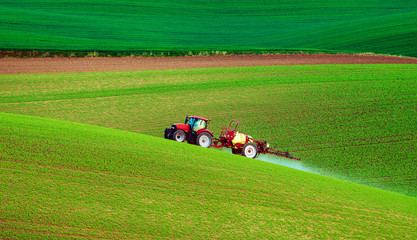 Farm machinery spraying insecticide to the green field, agricultural natural seasonal spring background