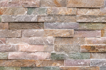 Steinwand aus groben, pastellfarbenen Verblendsteinen 