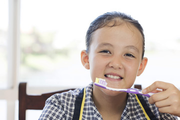 a school girl is brushing her teeth