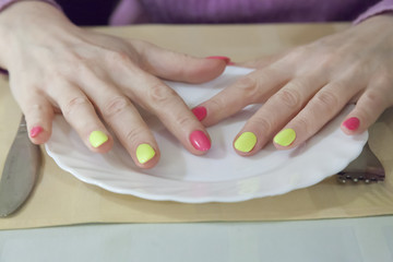 female hands with beautiful manicure on a white plate