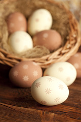 Easter eggs and wicker basket on wooden table