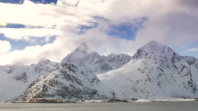 Time lapse of clouds moving over snow covered mountains at a fjord in the Lofoten islands region in Norway during winter