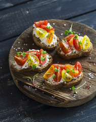 Tomato and cheese bruschetta on a rustic wooden cutting board. Healthy breakfast, snack or appetizer with wine