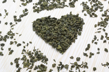 Green tea leaf in shape heart  on  wooden  background