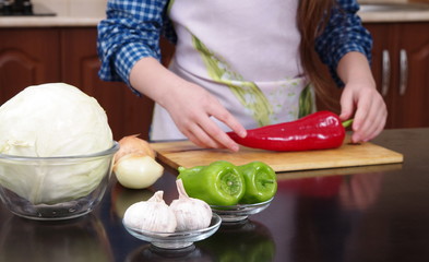 Little girl is cutting vegetables for salad closeup