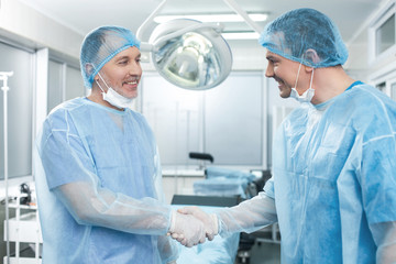 Cheerful two doctors congratulating each other with handshake