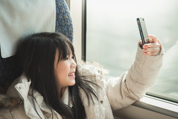 Little asian girl smiling and sharing social media in a smart ph