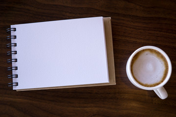 Open a blank white notebook with hot coffee on table