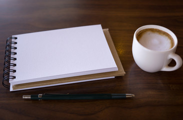 Open a blank white notebook with hot coffee on table