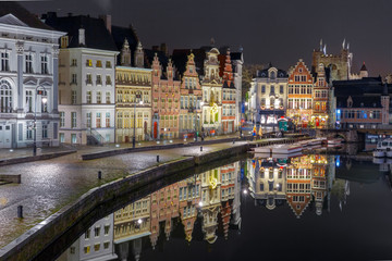 Picturesque medieval building on the quay Korenlei with reflections in Ghent town at night, Belgium