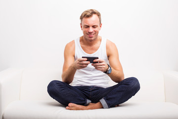 Man sitting in lotus position on couch and using his smartphone