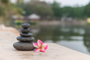 Fototapeta na wymiar zen stones with frangipani flower on public park background