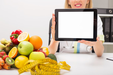 Tape measure, vegetables, and doctor holding tablet with blank screen
