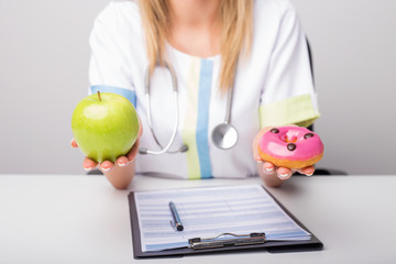 Dietary doctor holding donuts and apple