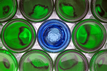 Glass blue bottle among green bottles. Concept of difference