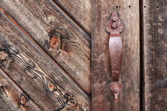Old rusty metal handle on wooden weathered door