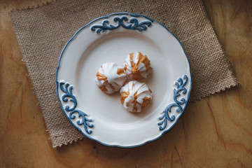 Home made choux cream on white plate. Over on wood table. Top view. with a white glaze. on wooden background