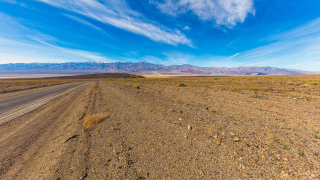 The track in dry desert. Mountain peaks covered with snow on horizon. Artist's Drive, Death Valley National Park