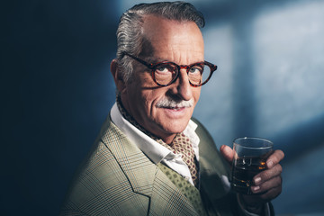 Retro 40s senior businessman holding glass of whiskey. Studio sh