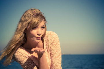 Lovely blonde girl blowing kiss outdoor by seaside