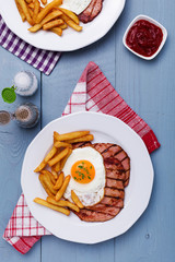 English breakfast with grilled ham, fried egg and french fries.