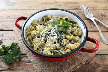ortica,pasta con foglie di ortica in tegame di metallo sfondo rustico